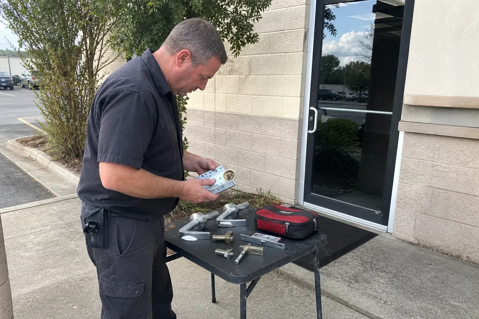 Technician examining detached commercial lock hardware on a table outside a shop entrance. — Business Lockout Service, Halton Hills